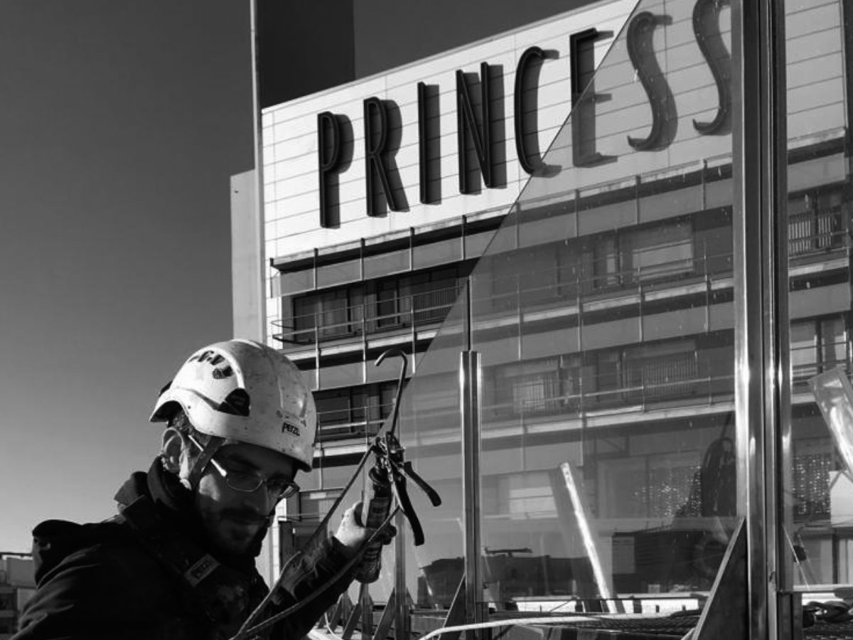 Imagen en blanco y negro de un trabajador de Imdeba reparando la fachada del hotel princess